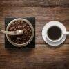 Coffee Beans in Grinder Beside Fresh Cup of Coffee