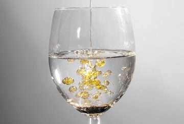 Oil separating from water in a glass, illustrating how oil-based THC tinctures do not dissolve in beverages.